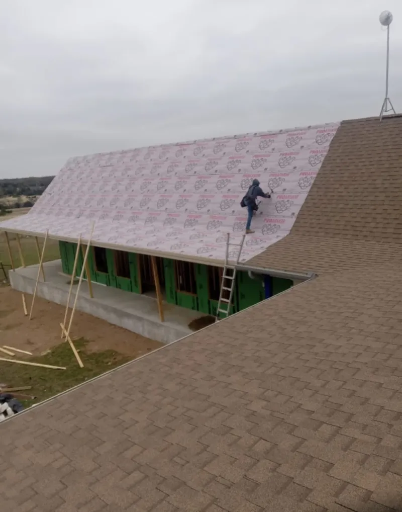 Worker preparing underlayment for a metal roof installation in Montclair